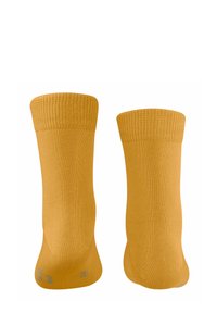 Des chaussettes jaunes vives sont présentées debout, mettant en valeur leurs poignets côtelés et leur texture lisse, soulignant un style décontracté et dynamique.
