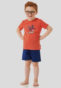 Oranges Baumwoll-T-Shirt mit blauer Cartoon-Grafik und Text, kombiniert mit marineblauen Shorts. Das Outfit hat eine lockere Passform und kurze Ärmel.