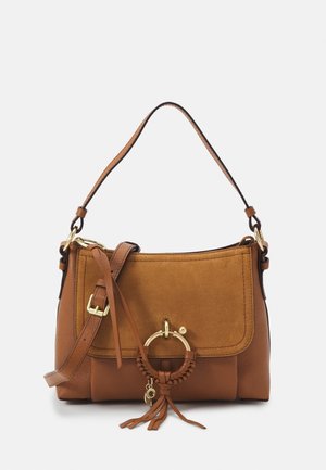 Bolso marrón de piel y ante con asa superior, correa de hombro ajustable, solapa frontal y anilla decorativa dorada con borlas.