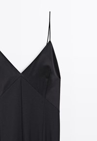 Schwarzes Satin-Kleid mit V-Ausschnitt und dünnen verstellbaren Trägern. Verfügt über ein strukturiertes Design und diagonale Nahtdetails. Glatte Textur.