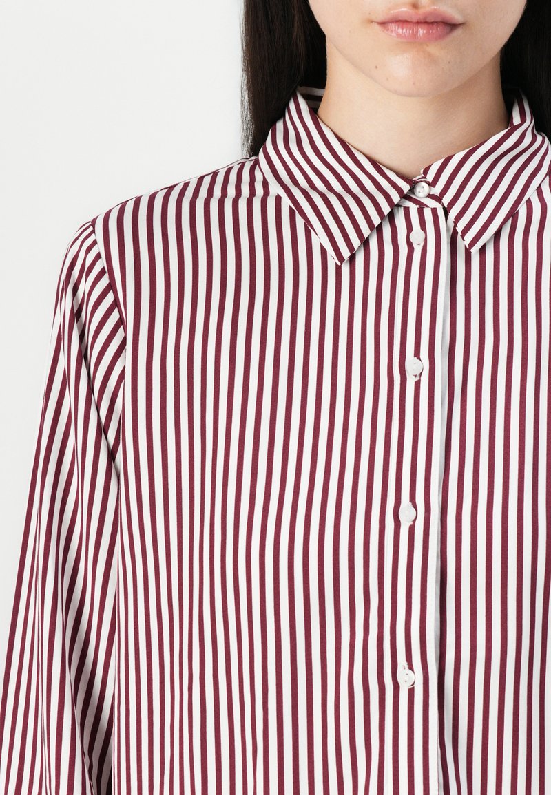 Bordeaux en witte gestreepte shirt met een puntige kraag, knoopsluiting aan de voorkant en lange mouwen, met een zachte stof structuur.