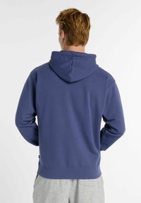 Felpa blu navy con cappuccio regolabile, maniche lunghe e vestibilità rilassata. Presenta un orlo e polsini a costine, realizzata in tessuto morbido e texturizzato.