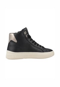 Zapatilla alta negra hecha de cuero suave con una suela de goma blanca texturizada y un acento metálico plateado en el talón. Presenta un diseño con cordones.