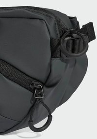 Borsa a tracolla nera in tessuto con sezioni imbottite, chiusura con zip, cinghie piatte e dettagli in D-ring metallici per opzioni di attacco.