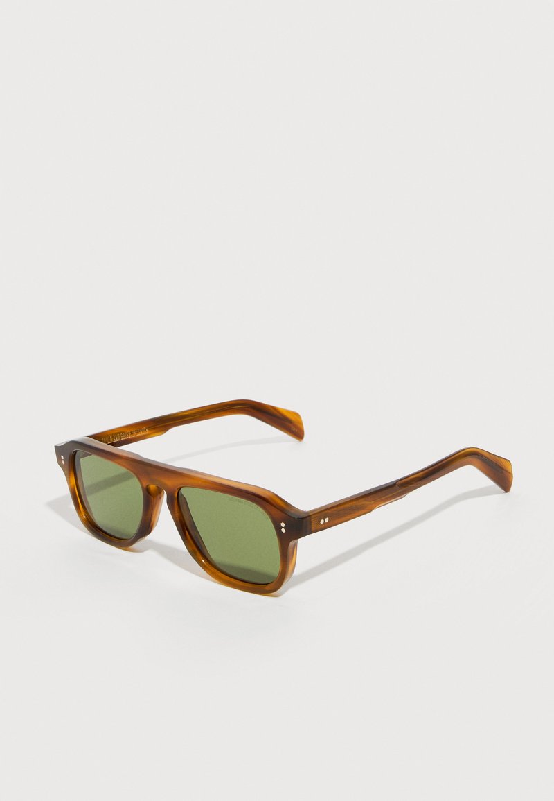 Καφέ ορθογώνια γυαλιά ηλίου tortoiseshell με σκούρους πράσινους φακούς, ελαφρώς κεκλιμένα σε λευκή επιφάνεια.