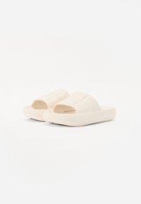 Sandale slide bej deschis cu un brâu căptușit, design cu vârf deschis, talpă texturată și o bază groasă, căptușită pentru confort.