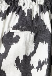 Svart och vit mönstrad tyg med en texturerad yta. Har en rynkad midja och en liten fickdetalj.