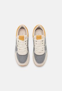 Lace-up sneakers with gray felt and cream leather accents, featuring a yellow heel tab and rubber sole. Smooth texture and rounded shape.