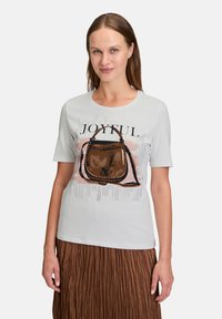 Lys grå kortærmet t-shirt med et grafisk motiv af en brun håndtaske og ordet "JOYFUL," med abstrakte designs i baggrunden.
