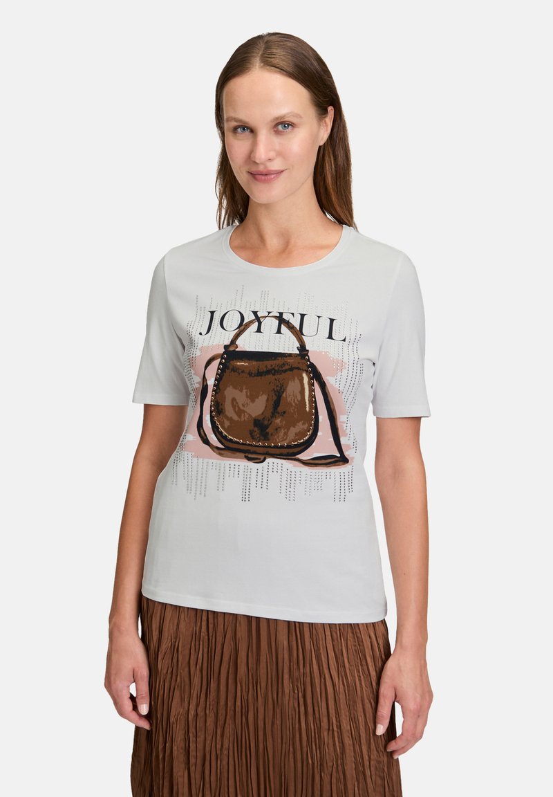 Lys grå kortærmet t-shirt med et grafisk motiv af en brun håndtaske og ordet "JOYFUL," med abstrakte designs i baggrunden.