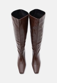 Καφέ μποτάκια πάνω από το γόνατο από συνθετικό δέρμα με τετράγωνη μύτη και ομαλή υφή. Διαθέτουν ομοιόμορφο, γυαλιστερό φινίρισμα χωρίς ορατά μεταλλικά μέρη.