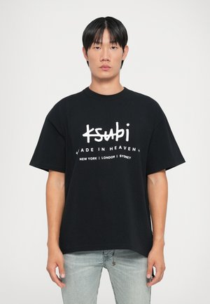 Svart oversized bomulls t-skjorte med hvit trykk som sier "ksubi MADE IN HEAVEN" med bynavn under. Korte ermer og rund hals.