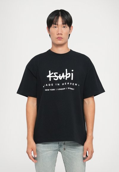 Fekete, oversized pamut póló, fehér felirattal, ami azt írja: "ksubi MADE IN HEAVEN", alatta városnevekkel. Rövid ujjú és kerek nyakú.