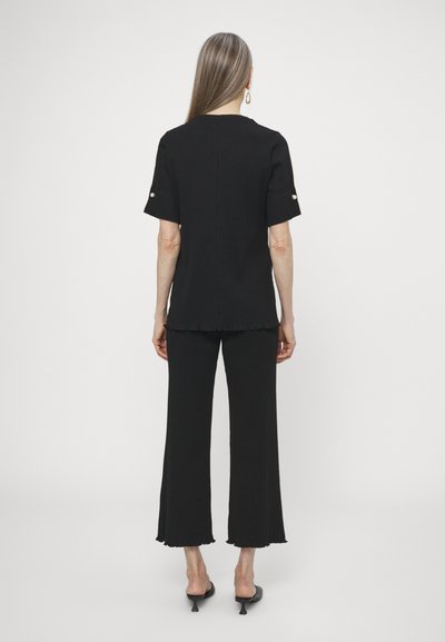 Black two-piece outfit consisting of a short-sleeve top and wide-leg pants. Fabric has a slight texture; pants feature a scalloped hem.