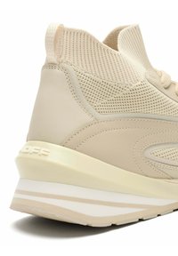 Zapatilla deportiva beige con parte superior de malla y detalles en cuero. Presenta un respaldo texturizado y un diseño de suela en capas en crema y blanco.