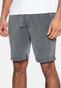 Shorts en mélange de coton gris avec un waistband à cordon de serrage, des ourlets roulés et un petit logo brodé sur la jambe gauche. Texture lisse.