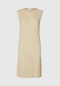 Robe sans manches en maille dans une douce teinte beige, présentant un motif zigzag texturé et des fentes sur les côtés pour faciliter les mouvements.