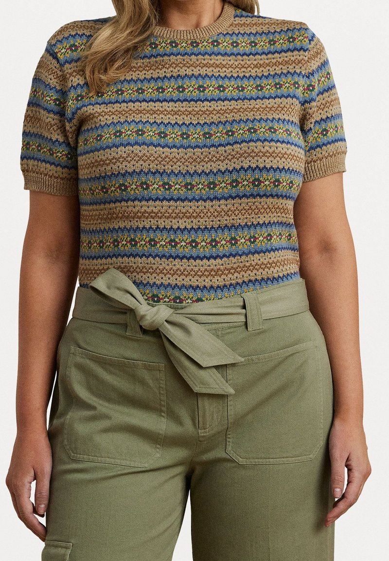 Stickad topp med korta ärmar som har ett flerfärgat randigt mönster i blått, grönt och brunt, kombinerad med olivgröna högmidjade byxor med en rosett i midjan.