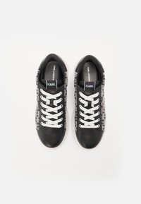 Sneaker in pelle nera con lacci bianchi, caratterizzati da un lato in tessuto a fantasia, punta rotonda e logo sulla linguetta e sulla soletta.