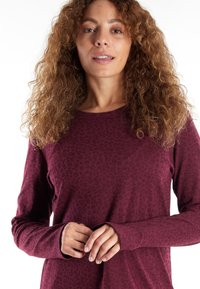 Long-sleeve top in burgundy with a textured floral pattern. Soft fabric with a relaxed fit and cuffed sleeves. Smooth round neckline.