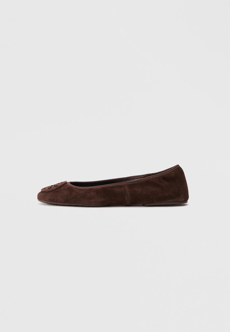 Ballerine en daim marron foncé avec bout rond et emblème décoratif à l'avant, vue de profil sur un fond uni clair.
