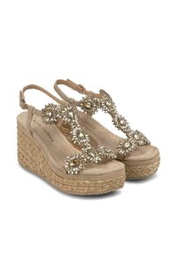 Sandales compensées beige avec un talon en jute texturé, dotées d'accents de bijoux décoratifs sur les brides et d'une semelle intérieure rembourrée.