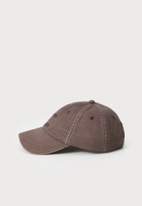 Cappello da baseball in cotone marrone con visiera curva, accenti ricamati sulla parte anteriore e sei fori di ventilazione. Finitura in tessuto testurizzato.