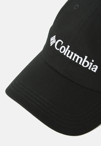 Casquette de baseball noire en coton avec une visière incurvée. Présente un logo "Columbia" brodé en blanc et des détails de couture contrastants.