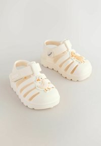 White rubber sandals with a duck design on the front, featuring multiple cutouts, a velcro strap, and a textured sole for traction.