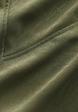 Olijfgroen stof met een gestructureerd oppervlak, voorzien van een gekreukeld patroon en nette, contrasterende naden. Geschikt voor kleding of stoffering.