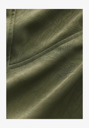 Olive green fabric with a textured surface, featuring a crinkled pattern and clean, contrasting seams. Suitable for clothing or upholstery.