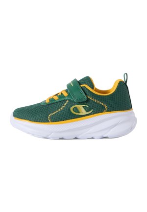 Zapatilla deportiva infantil verde y amarilla con suela blanca, parte superior de malla, tira de Velcro y lengüeta en el talón.
