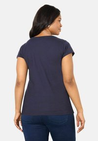 T-shirt blu navy a maniche corte con scollatura rotonda, tessuto morbido e vestibilità rilassata, indossato con jeans blu scuro.