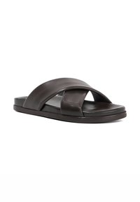 Brown leather slide sandal with crossed strap design, flat sole, minimalistic shape, and smooth texture. No embellishments or patterns.