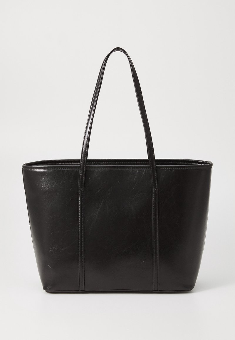 Sac cabas en cuir noir avec deux longues anses et un corps rectangulaire lisse et structuré sur un fond uni.
