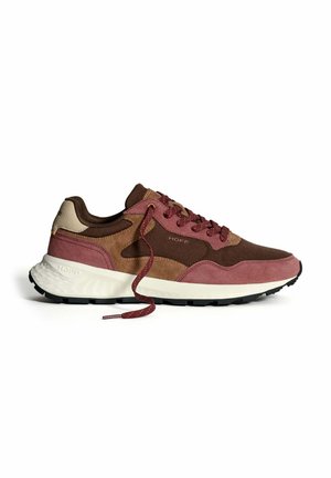 Basket avec des panneaux en daim marron, beige et mauve, semelle blanche et lacets mauves assortis défaits, sur un fond blanc.