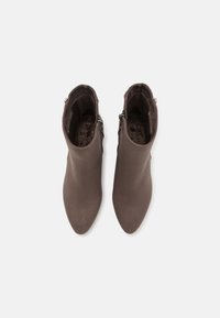 Bottines marron en matériau lisse, avec un design à bout pointu, fermeture éclair latérale et intérieur doux et texturé.