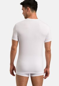 White short-sleeve top with a fitted design, smooth texture, and crew neck, paired with matching white shorts. Clean and minimal look.