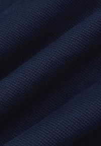 Granatowy materiał prezentujący teksturowany splot z subtelnymi wzorami, z miękkimi fałdami i gęstą, równomierną powierzchnią.