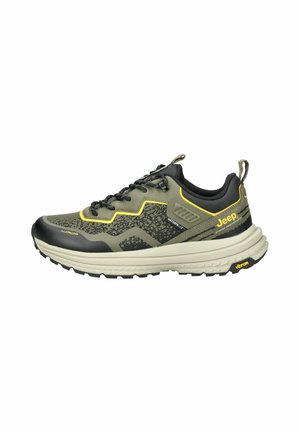 Sneaker da uomo impermeabile in verde scuro e nero, con tessuto testurizzato, dettagli gialli e suola spessa e scolpita con branding prominente.