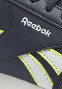 Reebok-sneaker med övre del i marinblått läder, vita och neon-gula accenter, texturerad yta och svarta snören. Har en framträdande logotyp.