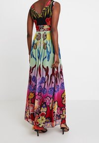 Robe longue à col en V, imprimé floral aux couleurs vives — corsage noir, dégradé vert et violet, accents floraux partout. Texture lisse.