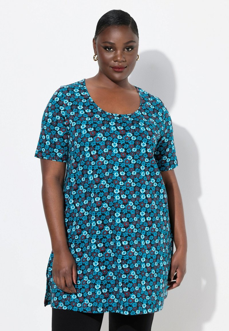 Tunic a maniche corte in un vivace tessuto blu con motivi floreali in blu, rosso e bianco. Presenta una scollatura a girocollo e spacchi laterali.