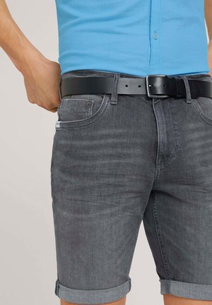 Shorts en denim gris avec un ourlet roulé, associés à une ceinture noire. Texture lisse et design ajusté, portés avec un polo bleu clair.