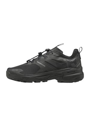 Chaussure de sport noire à coupe basse avec semelle texturée, système de laçage rapide et languettes sur la languette et le talon pour un enfilage facile.