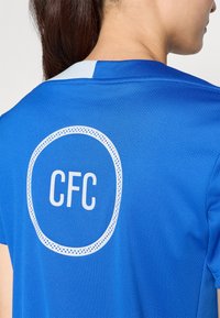 Sininen urheilupaita hengittävästä kankaasta, jossa on pyöreä valkoinen logo selässä, jossa lukee "CFC", ja vaaleansininen kontrastikaulus.