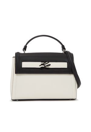 Black and white structured handbag with top handle, detachable shoulder strap, and metallic brand logo on front flap.