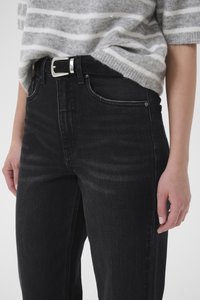 Μαύρο τζιν από denim με ψηλή μέση, με κλασικό στυλ πέντε τσεπών και ραφές σε αντίθετο χρώμα. Φοριέται με γκρι ριγέ πλεκτό τοπ.