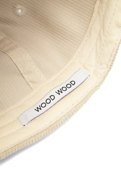 Sárga szövet sapka bordázott textúrával, amelyen egy fehér "WOOD WOOD" címke van felvarrva a belső pánt mentén.