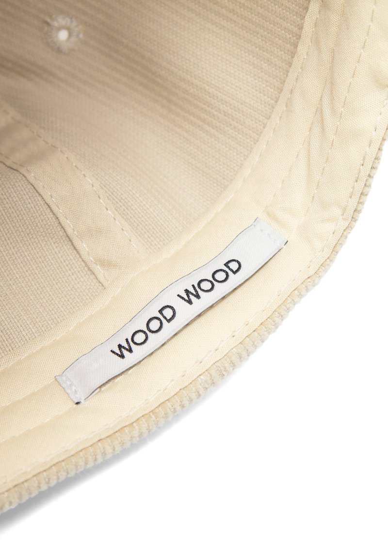 Tan fabric cap with ridged texture, featuring a white "WOOD WOOD" label stitched along the inner band.